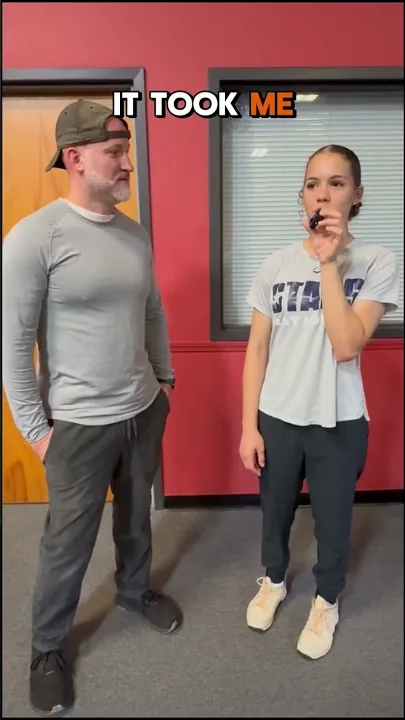 Coach Aaron talking with a softball athlete in the gym